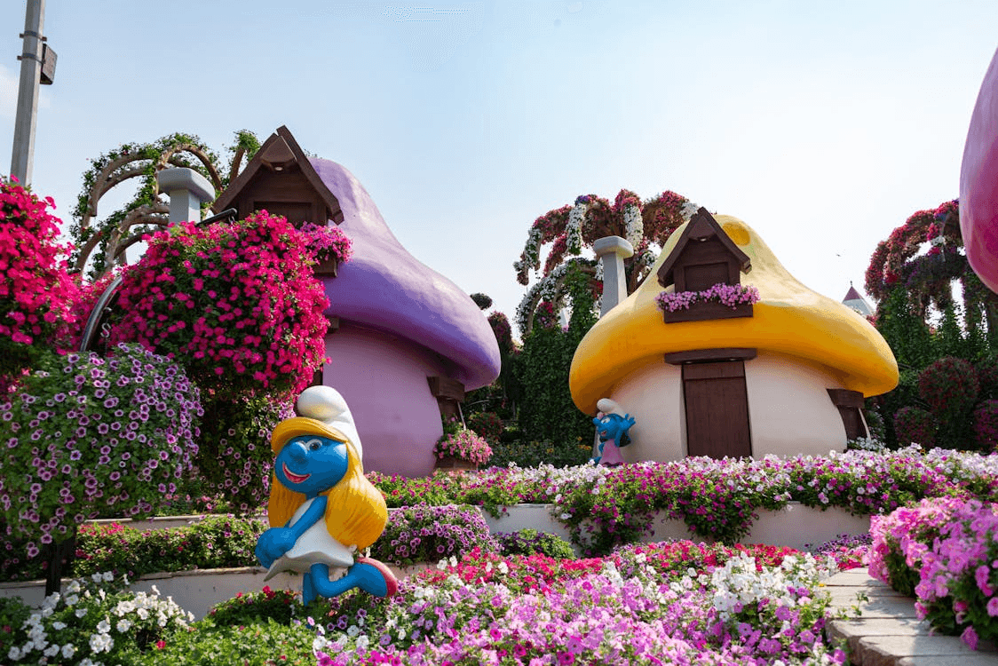 Smurf-themed area in a Dubai theme park surrounded by colourful flowers.