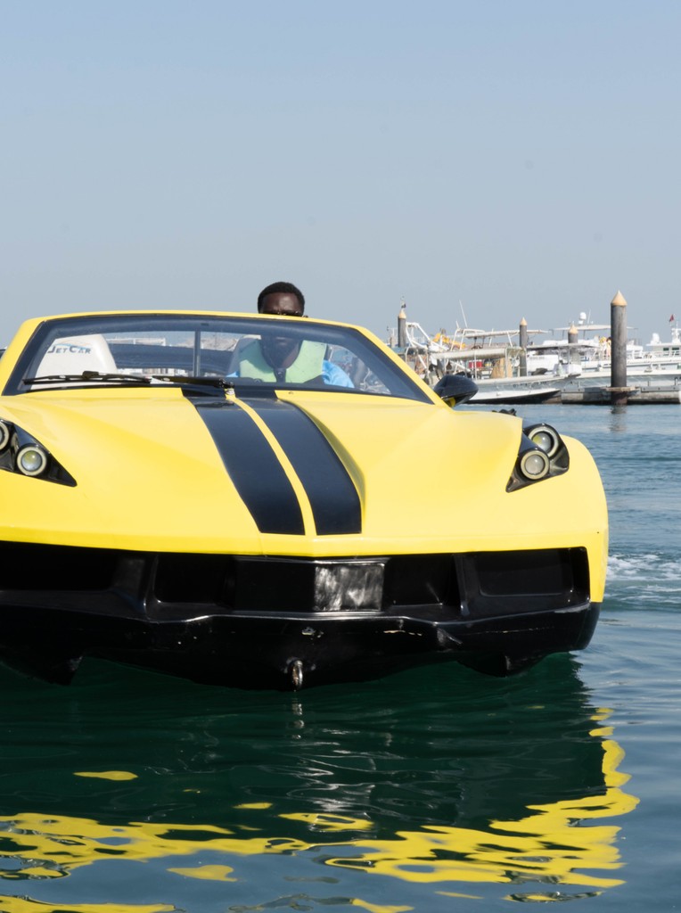 Yellow jet car cruising on the water during a ride in Dubai with marina views.