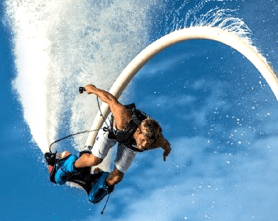 Man flyboarding over the water in Dubai while wearing safety gear and a life jacket