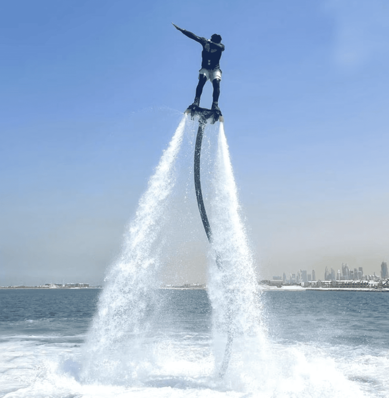 Man flyboarding high above the water with powerful jets, showcasing the thrill of the experience in Dubai.
