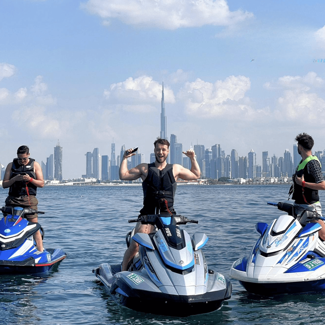 Three men on jet skis in front of the Dubai skyline with Burj Khalifa in the background, posing during a guided tour.