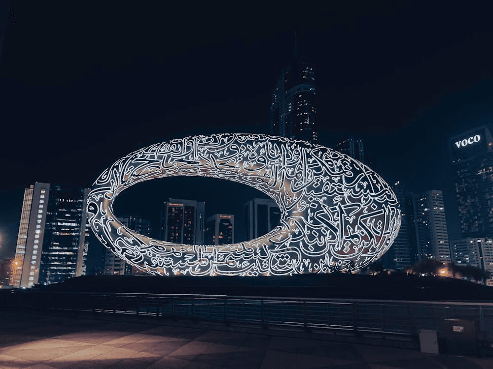 Museum of the Future lit up at night with Dubai skyline in the background.