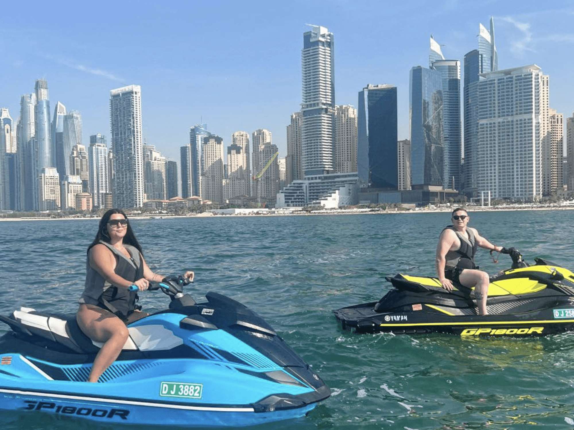 Two riders on jet skis enjoying a view of Dubai Marina’s skyscrapers from the water