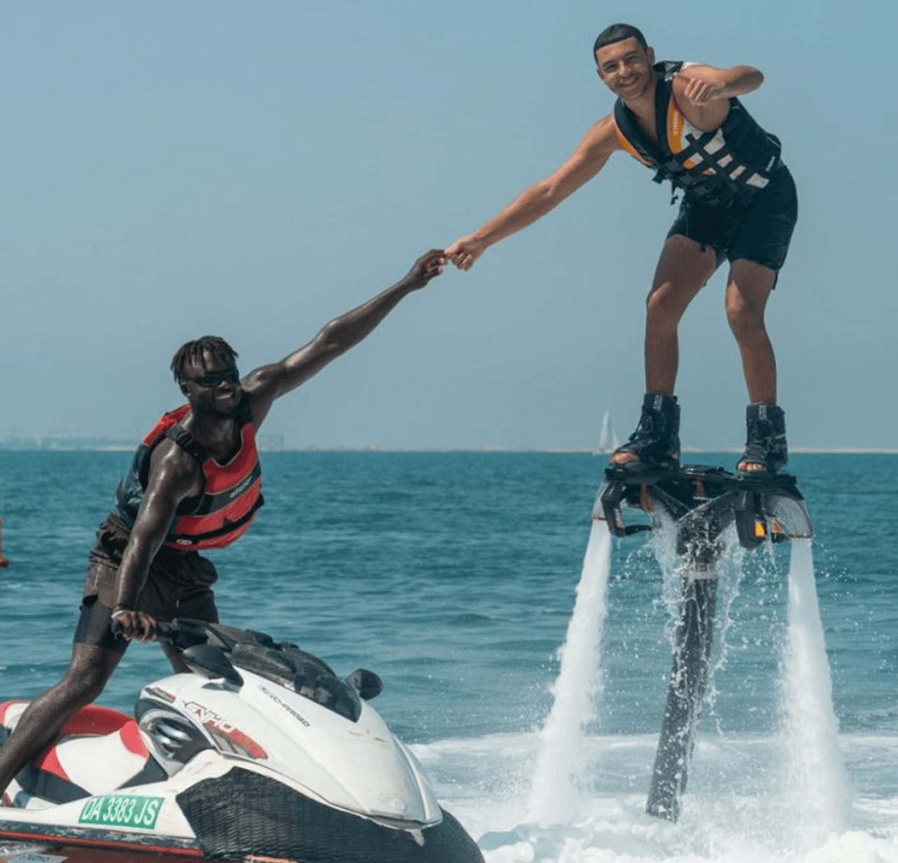 Beginner using a flyboard connected to a Jet Ski during a guided session in Dubai