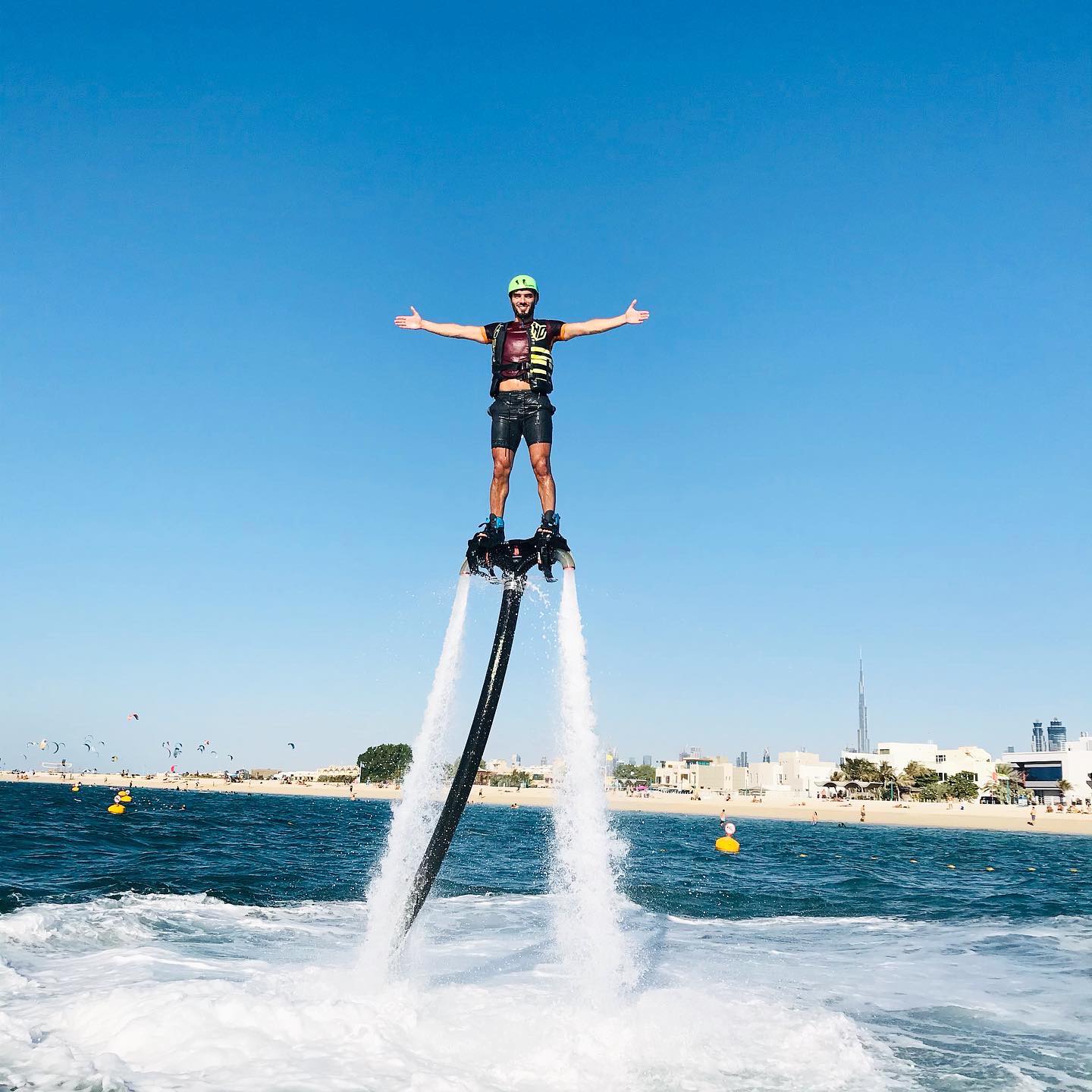 Man flyboarding above the sea in Dubai, wearing a helmet and life vest, with the Ride in Dubai