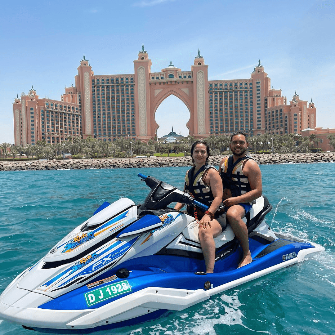 A couple on a blue and white jet ski in front of Palm Jumeirah 90 minutes tour