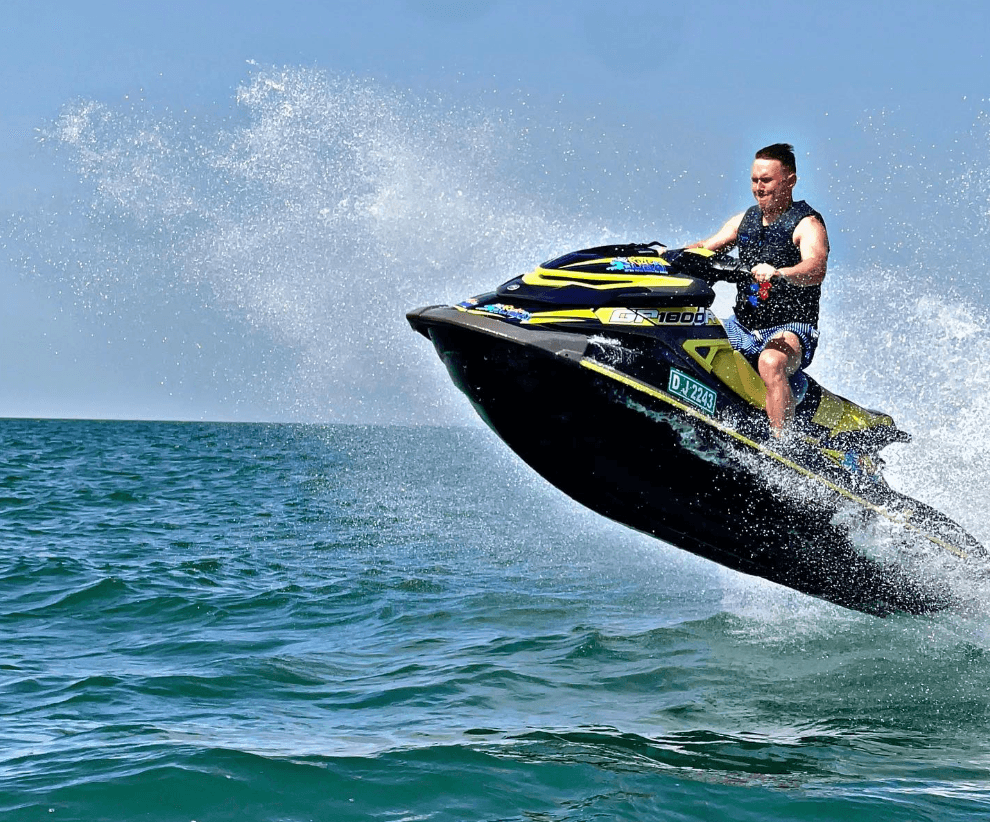 Man riding a jet ski at high speed over the sea in Dubai, celebrating his birthday with a watersport activity.