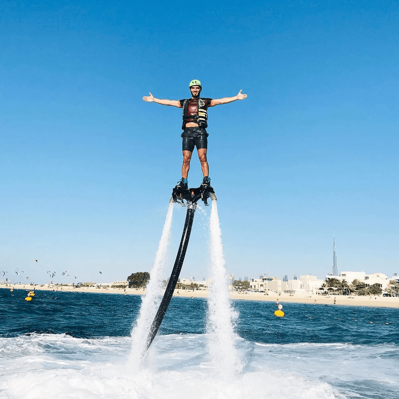 First-time rider balancing on a flyboard above the water, wearing safety gear in Dubai