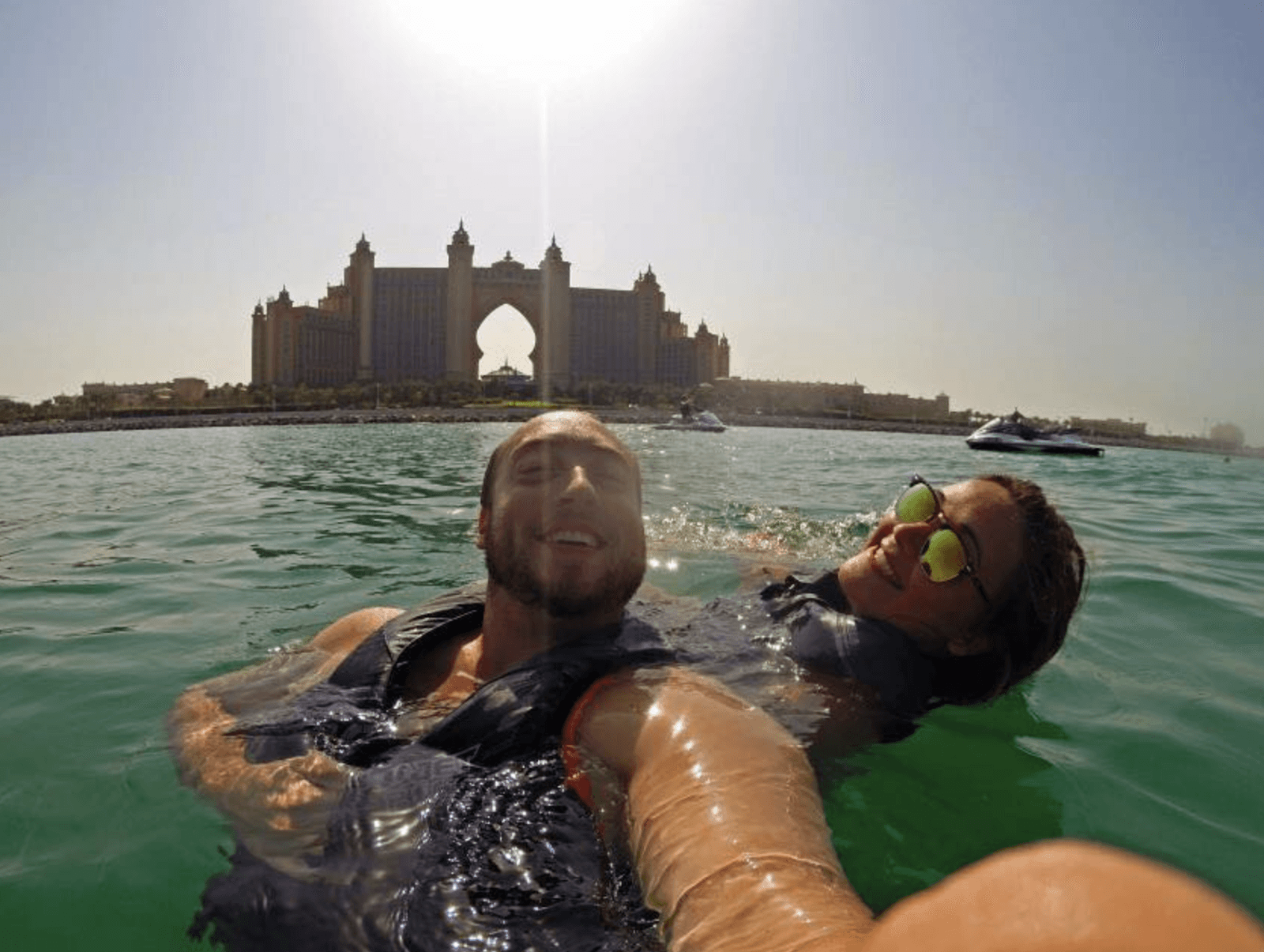 Couple enjoying fun beach water sports in Dubai, floating in the water near Atlantis with jet ski water sports offered by Ride in Dubai. Follow our packing checklist for water sports in Dubai.