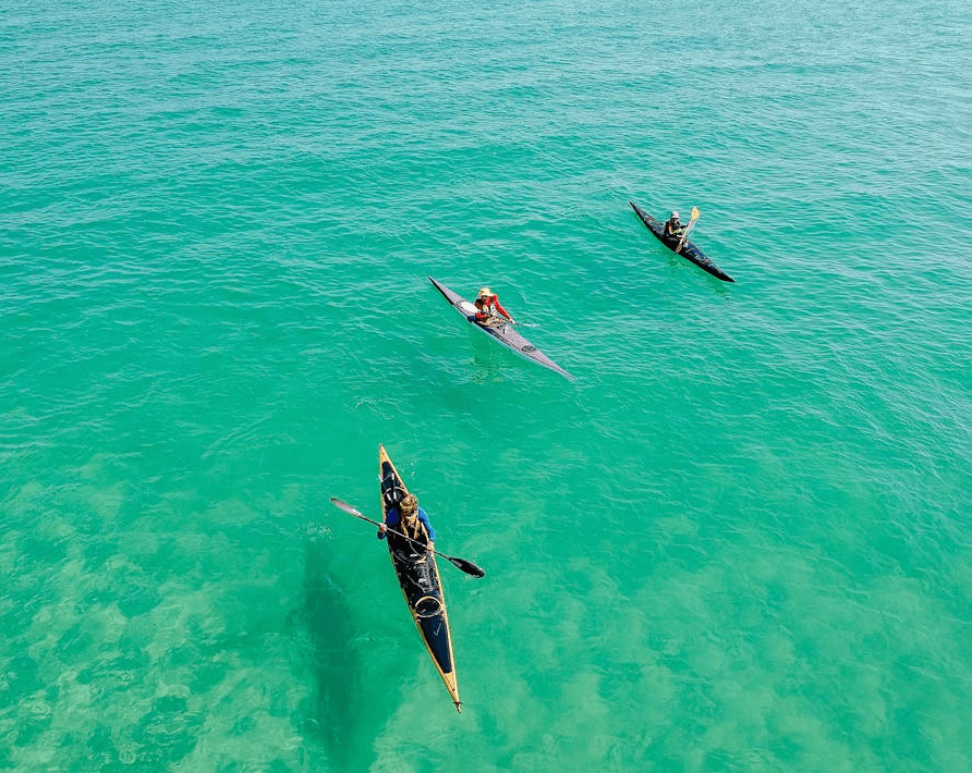 Three people kayaking on clear turquoise water in Dubai during a recreational watersports activity