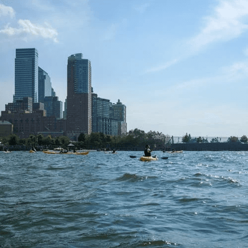 People kayaking with city buildings in the background, a calm and scenic water sport in Dubai
