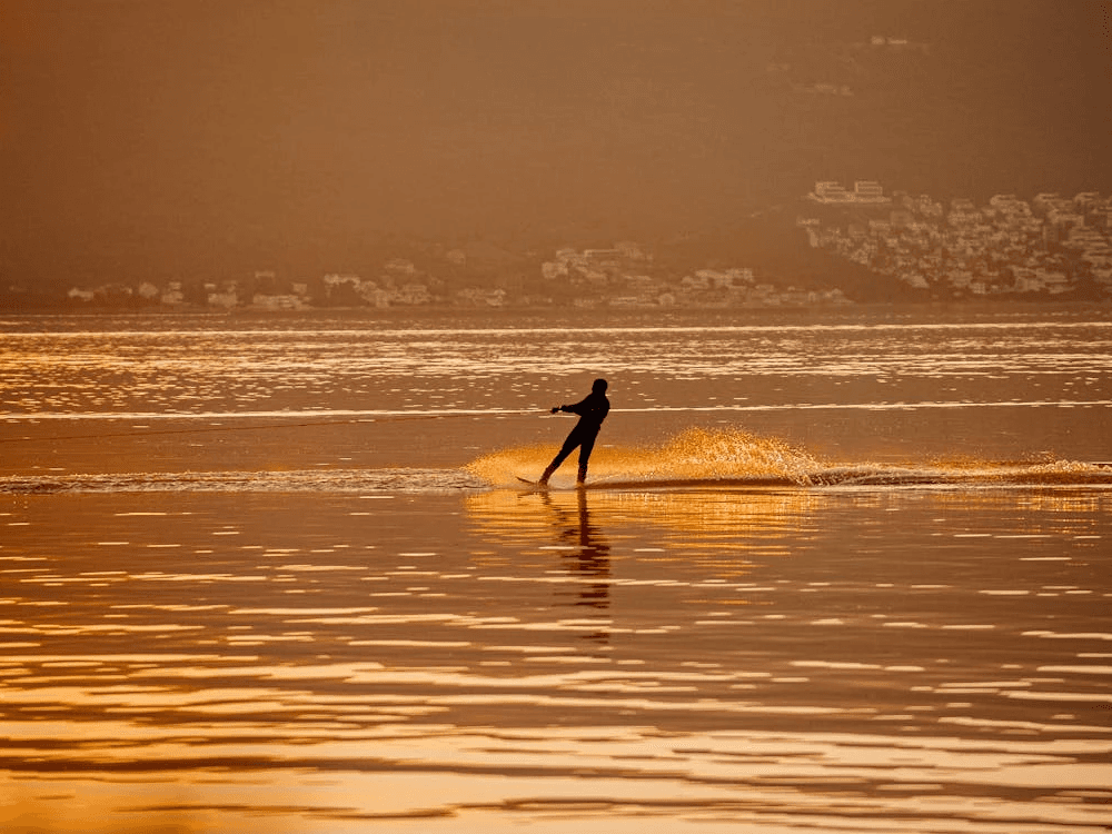 A person water skiing at sunset, a fast-paced water sport in Dubai ideal for adventure seekers.