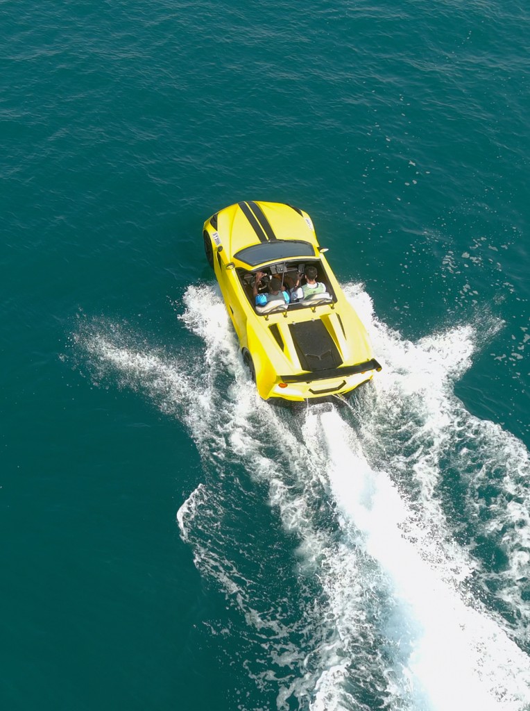 Aerial view of a yellow jet car cruising on the water during a thrilling ride in Dubai, leaving waves behind on the Arabian Gulf.